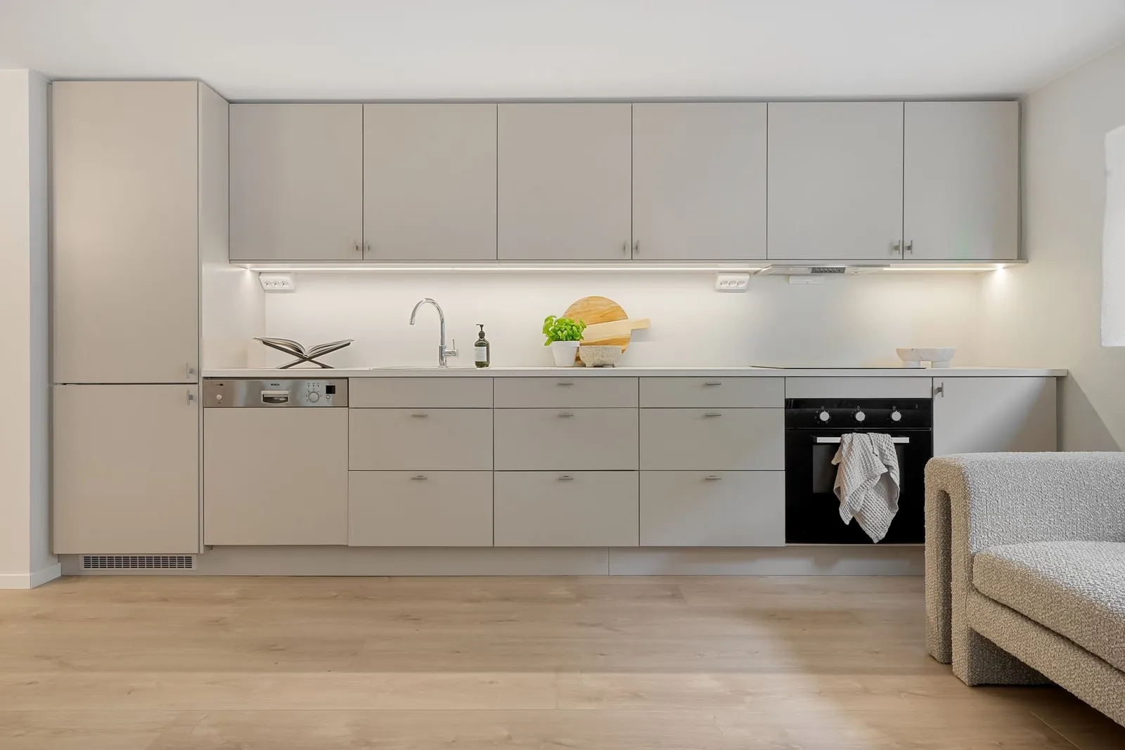 A clean, bright kitchen with pale cabinets and a wood floor